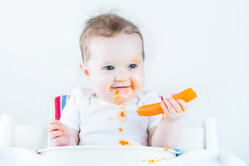 Sweet baby eating her first carrot