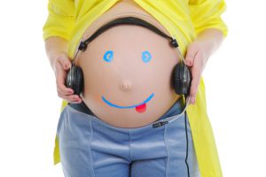 Mujer embarazada con auriculares en la tripa