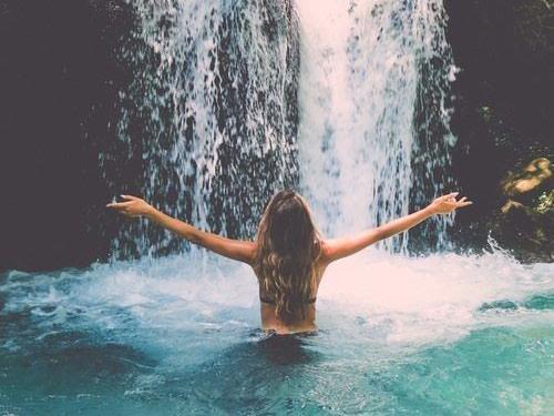 Chica bañándose en cascada